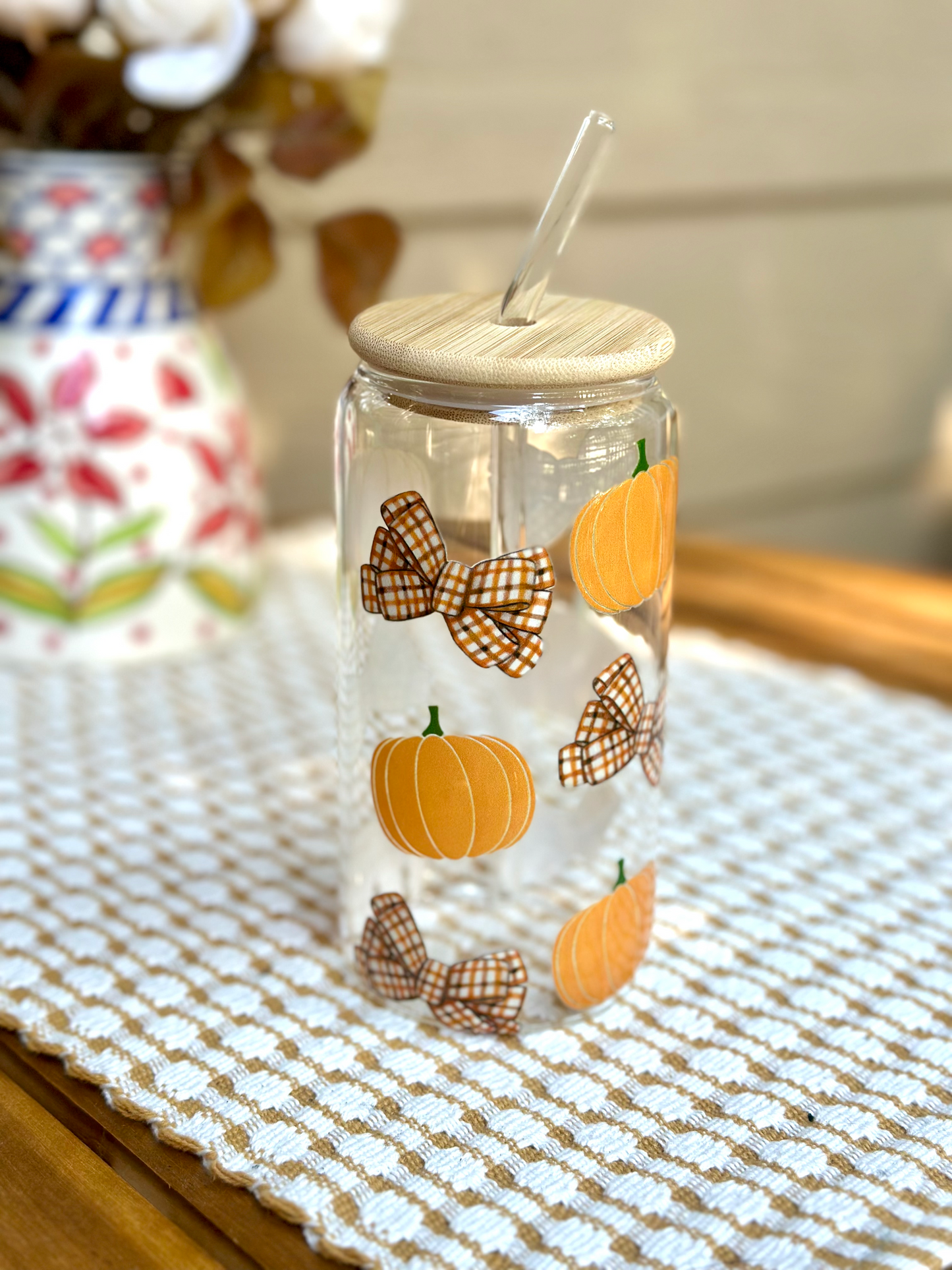 Glass cup designed with orange pumpkins and plaid bows for fall and halloween 